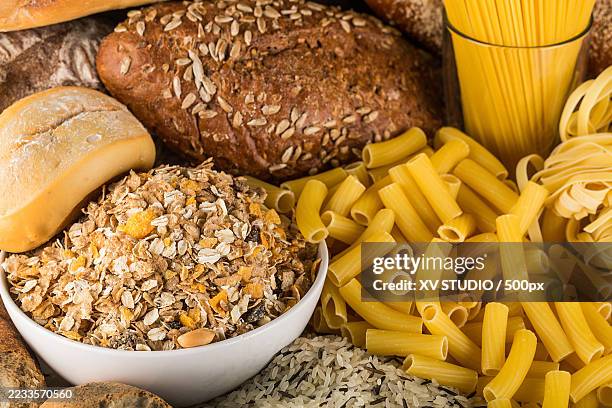assorted bread, pasta, and cereal on a table - carbohidrato fotografías e imágenes de stock