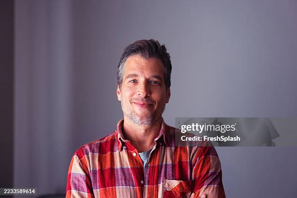 confident middle-aged man smiling while wearing casual plaid shirt indoors - red flannel stock pictures, royalty-free photos & images
