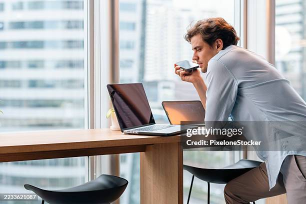 man using his smartphone to interact with an ai helping to develop coding in modern office. - mobile developer stock pictures, royalty-free photos & images