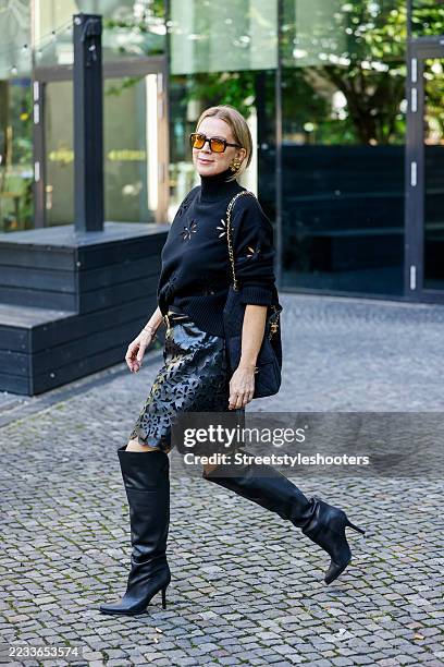 Tamara Graefin von Nayhauss wearing a black turtle neck with flower cut outs by Maison Common, a black leather skirt with flower cut outs by Maison...