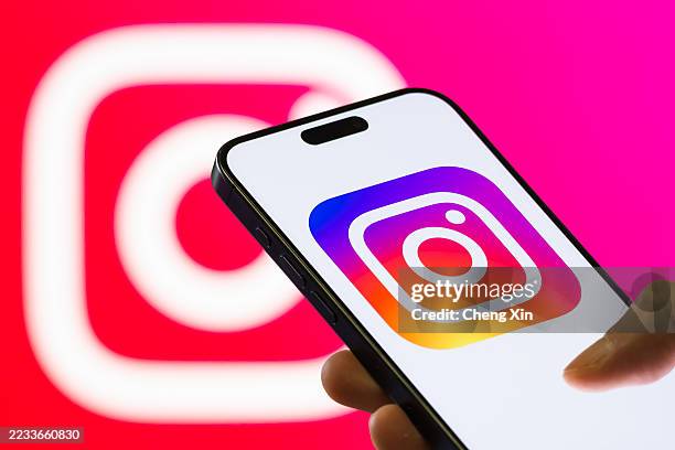 In this photo illustration, a smartphone held in a hand shows the logo of Instagram, a popular social media and photo-sharing platform owned by Meta...