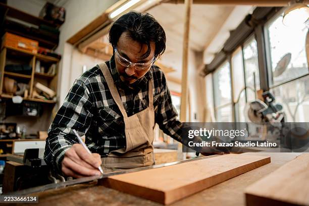mature carpenter measuring wood in a workshop - timmerman stockfoto's en -beelden