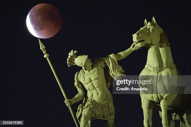 Full moon rises behind a sculpture of a chariot at the Palace Square in Saint Petersburg, Russia during total lunar eclipse on September 7, 2025.