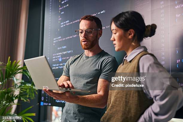 zwei junge programmierer diskutieren im büro über code auf laptop - programmierer stock-fotos und bilder