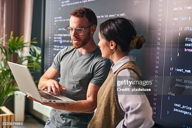 zwei junge programmierer diskutieren im büro über code auf laptop - programmierer stock-fotos und bilder
