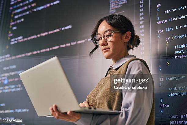 giovane programmatore che analizza il codice su laptop e grande schermo in un ufficio moderno - programmatore di computer foto e immagini stock