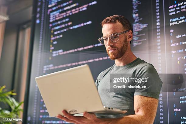 fokussierter softwareentwickler, der an einem laptop mit code arbeitet, der in einem modernen büro auf dem bildschirm angezeigt wird - software developer stock-fotos und bilder