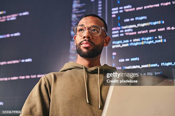 fokussierter softwareentwickler, der an einem laptop mit code arbeitet, der in einem modernen büro auf dem bildschirm angezeigt wird - programmierer stock-fotos und bilder