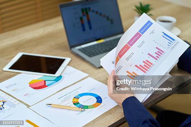 businesswoman analyzing financial reports and charts at office desk - financial report stock pictures, royalty-free photos & images