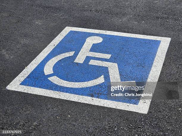 painted icon indicating wheelchair accessible parking space in car park - simbolo internazionale di accesso foto e immagini stock