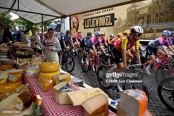 Kirstie Van Haaften of Netherlands and Team Cofidis Women and a general view of the peloton passing in front of a cheese stand prior to the 27th...