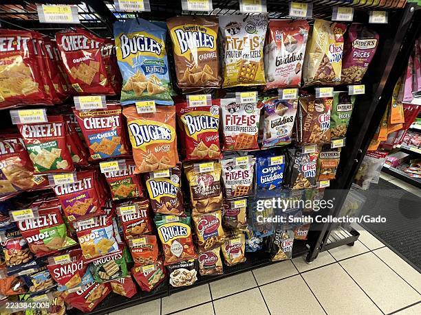 Snack aisle display with packaged chips, pretzels, and crackers including Cheez-It, Bugles, and Chex Mix inside a convenience store, Prunedale,...