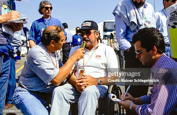 Surrounded by media, Clay Regazzoni speaks into a microphone as he is interviewed in the paddock during the San Marino Grand Prix at Autodromo Enzo e...