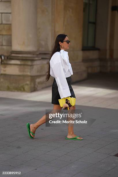 Jenny is seen wearing a white, straight-cut, oversized blouse, extended slit cuffs with white buttons and a removable flower brooch made from a...