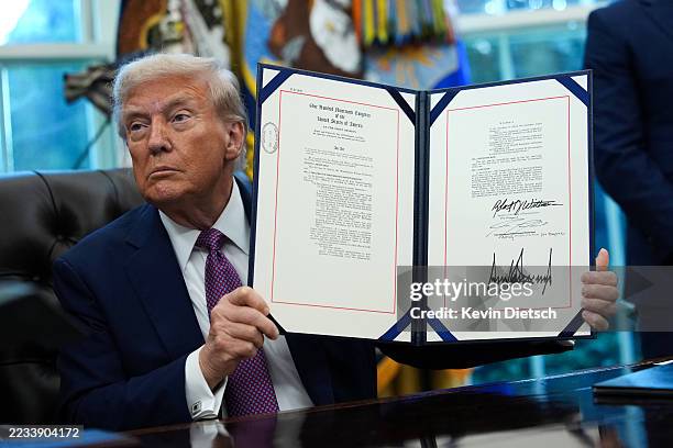 President Donald Trump displays a signed executive order amending the Fair Credit Reporting Act during a press availability in the Oval Office of the...
