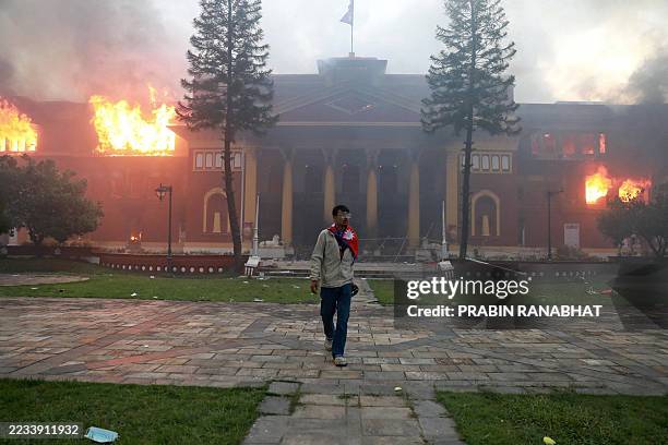 Man is draped in the Nepal national flag as a fire rages through the president's office in Kathmandu on September 9 a day after a police crackdown on...