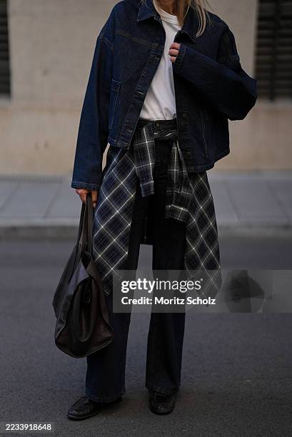 Mirja Klein is seen wearing a classic white crew-neck T-shirt from COS; a dark blue oversized MalleMW Casual denim jacket with button closure, shirt...