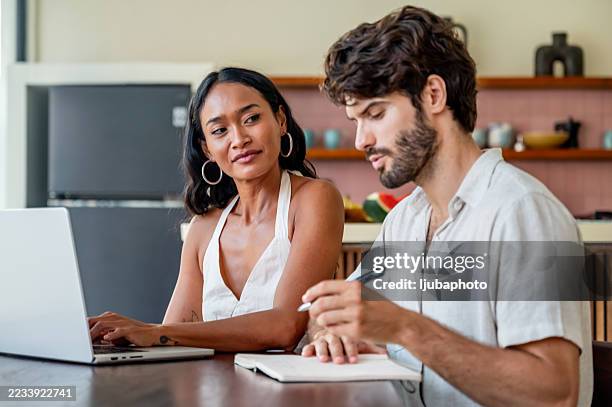 two people collaborating in a modern kitchen environment with laptops and notebooks - employability stock pictures, royalty-free photos & images