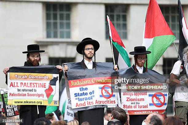 Members of the Ultra-Orthodox Jewish community hold placards and Palestinian flags during a demonstration outside Downing Street gates, in central...