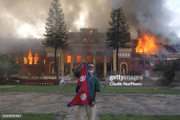 Nepali protestor poses for a photo in front of the Presidential palace in Kathmandu, Nepal, on September 9 as it is set ablaze on the second day of...