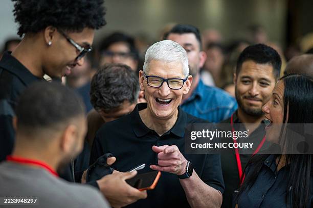 Apple CEO Tim Cook laughs as he talks with an Apple employee during Apple's "Awe-Dropping" event at the Steve Jobs Theater on the Apple Park campus...