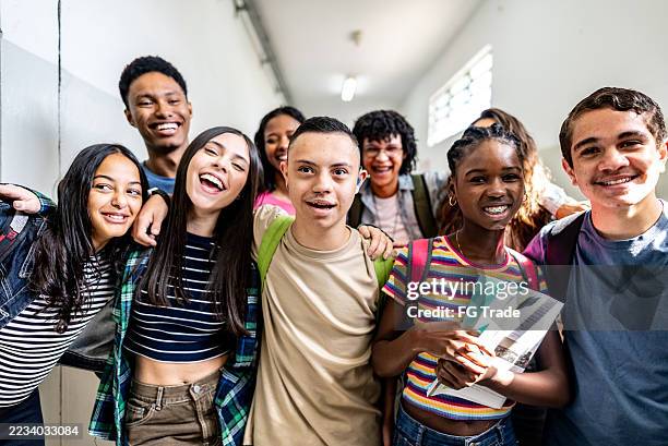 portrait of diverse group of students smiling together in school hallway - high school student stock pictures, royalty-free photos & images