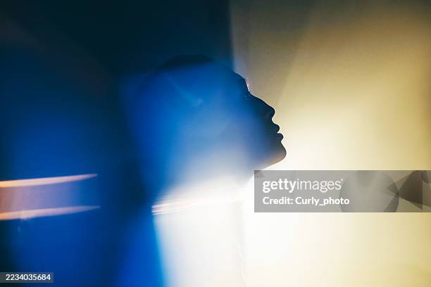 a close-up profile of a person is illuminated by a dynamic and powerful beam of light with blue and yellow tones. - information equipment stock pictures, royalty-free photos & images