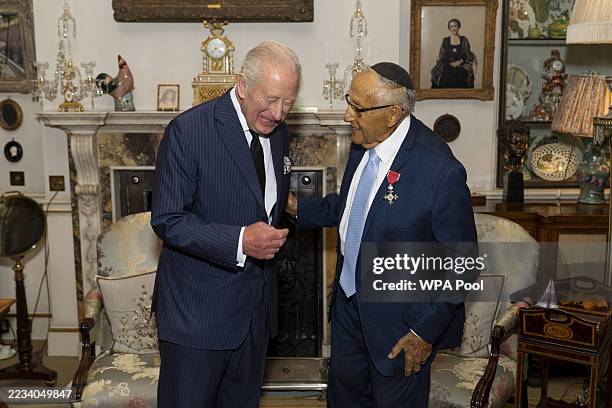 King Charles III reacts as he holds an audience with Mr. Manfred Goldberg after he invested him with the Insignia of a Member of the Most Excellent...