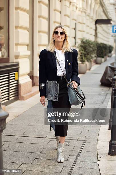 Julia Kareva wears two colour denim skirt, white T-shirt, blue denim jacket and blue bag and silver tabi or split toe shoes during the Budapest...