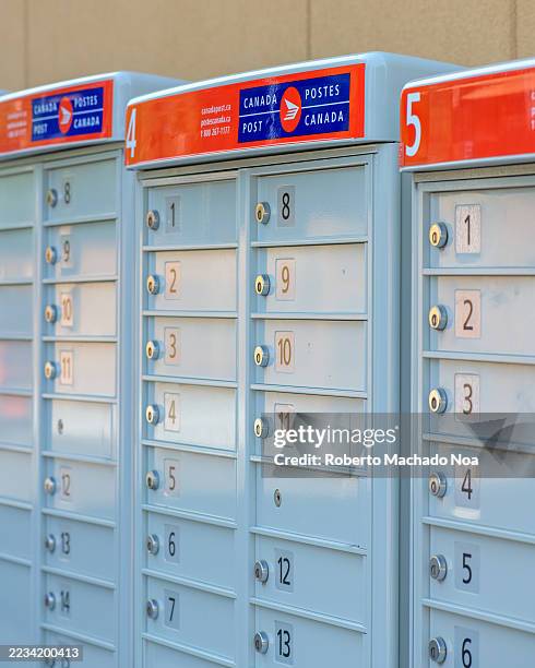 Rows of Canada Post community mailboxes labeled with numbered compartments and red and blue signage.