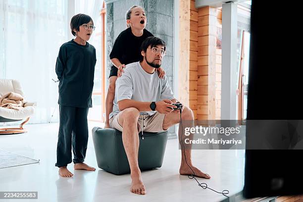 the family enthusiastically plays video games on the console. father, son and daughter. - modern manhood stock pictures, royalty-free photos & images