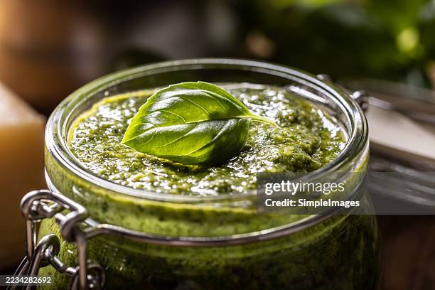 close-up view of a glass full of fresh green basil pesto with a leaf on top. - pistou photos et images de collection
