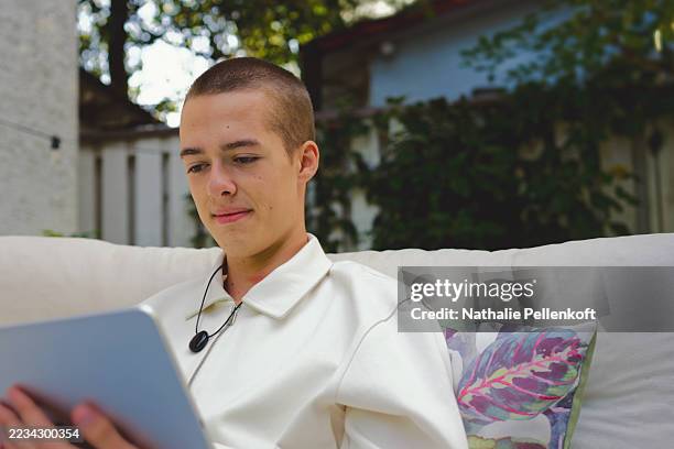 teenager verbindet sich mit zukunftstechnologie über ein tragbares ki-gerät und entspannt sich an einem warmen, sonnigen nachmittag in einem grünen garten - websurfen stock-fotos und bilder