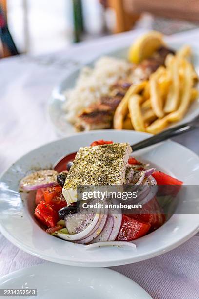close-up of a traditional greek souvlaki dish with chips and greek salad - greek salad stock pictures, royalty-free photos & images
