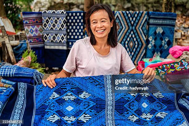 laotian woman selling traditional textiles on a morning market, luang prabang, laos - vientiane stock pictures, royalty-free photos & images