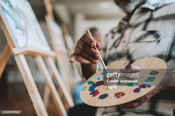 close-up of hands painting a picture in the painting studio - palet stockfoto's en -beelden