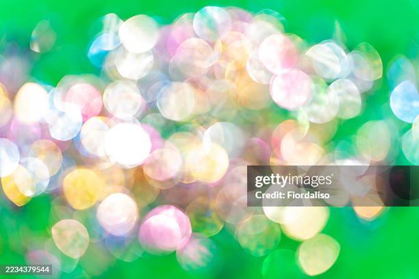 vivid and colorful bokeh spheres on a lively green background - rainbow confetti stock pictures, royalty-free photos & images