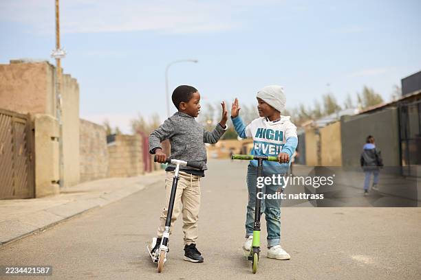 boys giving high-five while playing outdoors - zuidelijk afrika stockfoto's en -beelden