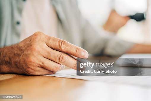 A close-up shot of an older person's hand holding a pen, pointing at a document or contract. The moment of decision-making, such as signing a contract or reviewing documents. A close-up shot of an older person's hand holding a pen, pointing at a document or contract. The moment of decision-making, such as signing a contract or reviewing documents.