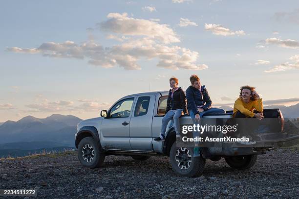 portrait of brothers sitting on pickup truck on mountain ridge at sunset - pick up truck stock pictures, royalty-free photos & images