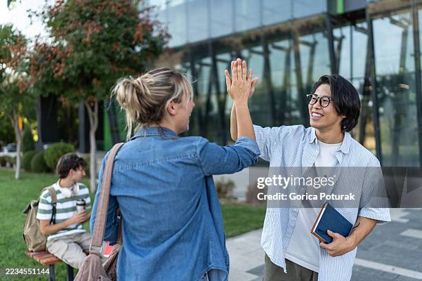 two happy students giving high five outdoors - encouragement stock pictures, royalty-free photos & images