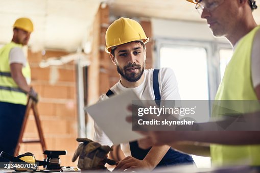 Manual workers using touchpad at construction site. Manual workers using touchpad at construction site.