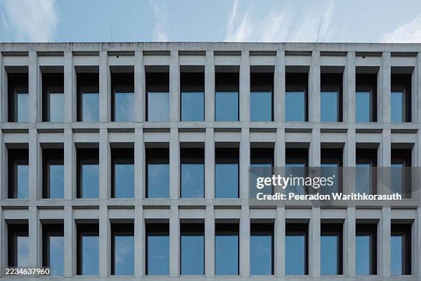 symmetrical facade of a modern brutalist building with a repeating window pattern. - brutalism stock pictures, royalty-free photos & images