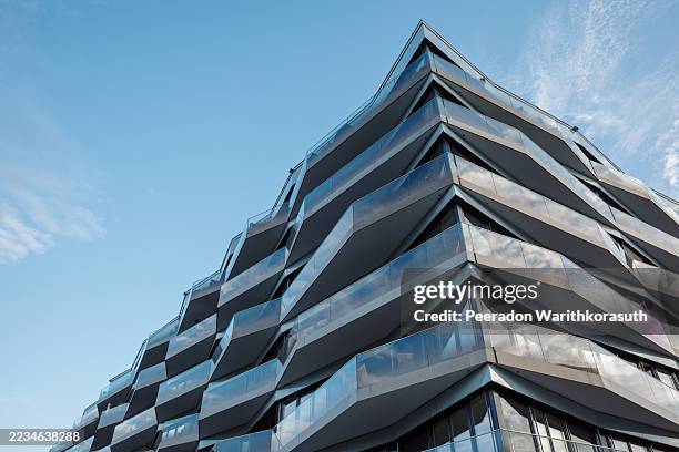 the unique architecture features a dynamic, crystalline structure with sharp, angular balconies and blue-tinted glass - sharp stock pictures, royalty-free photos & images