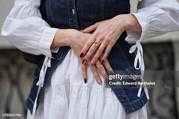 Marion Felicite wears a dark blue denim corset by & Other Stories layered over a white long-sleeve shirt dress by Sister Jane, a gold ring, and...