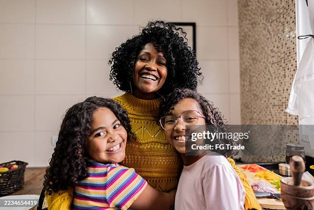 porträt von mutter und töchtern, die sich zu hause in der küche umarmen - kind vor der pubertät stock-fotos und bilder