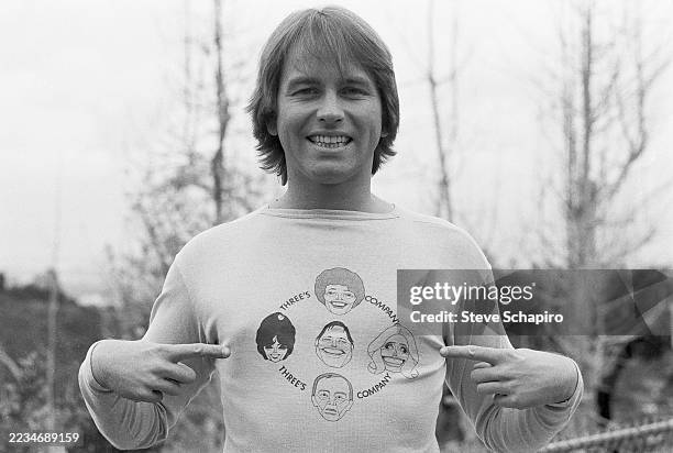 Portrait of American actor John Ritter as he poses outdoors, Los Angeles, California, circa 1977. He points to his shirt which references the...