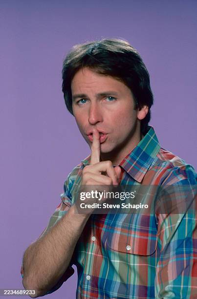 Portrait of American actor John Ritter as he holds a finger to his lips, Los Angeles, California, March 1978.