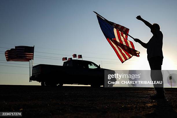 Man holding a US flag raises a fist as a rally in memory of right-wing activist Charlie Kirk drives past on September 13, 2025 in Surprise, Arizona....