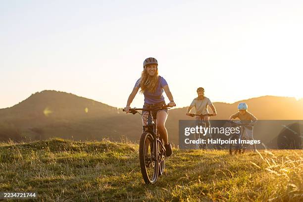 parents and boy having fun, riding down the hill during evening cycling trip, front view. - city break stock pictures, royalty-free photos & images